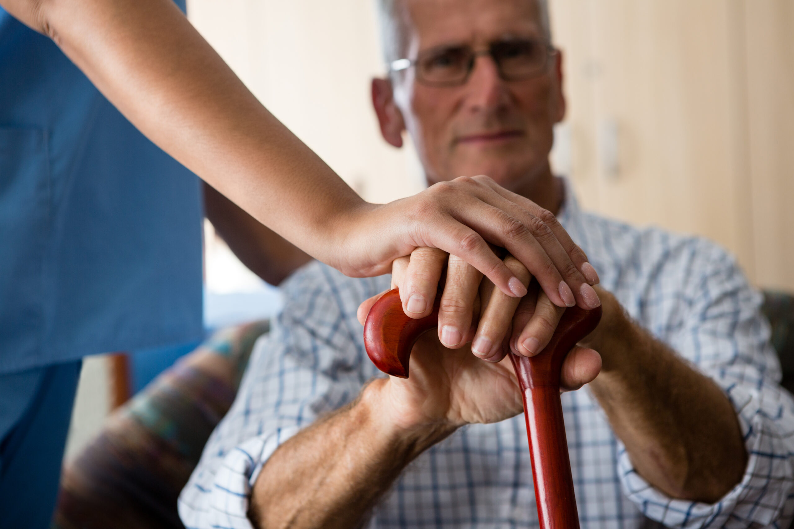 Close up of female doctor and senior man hands holding walking cane