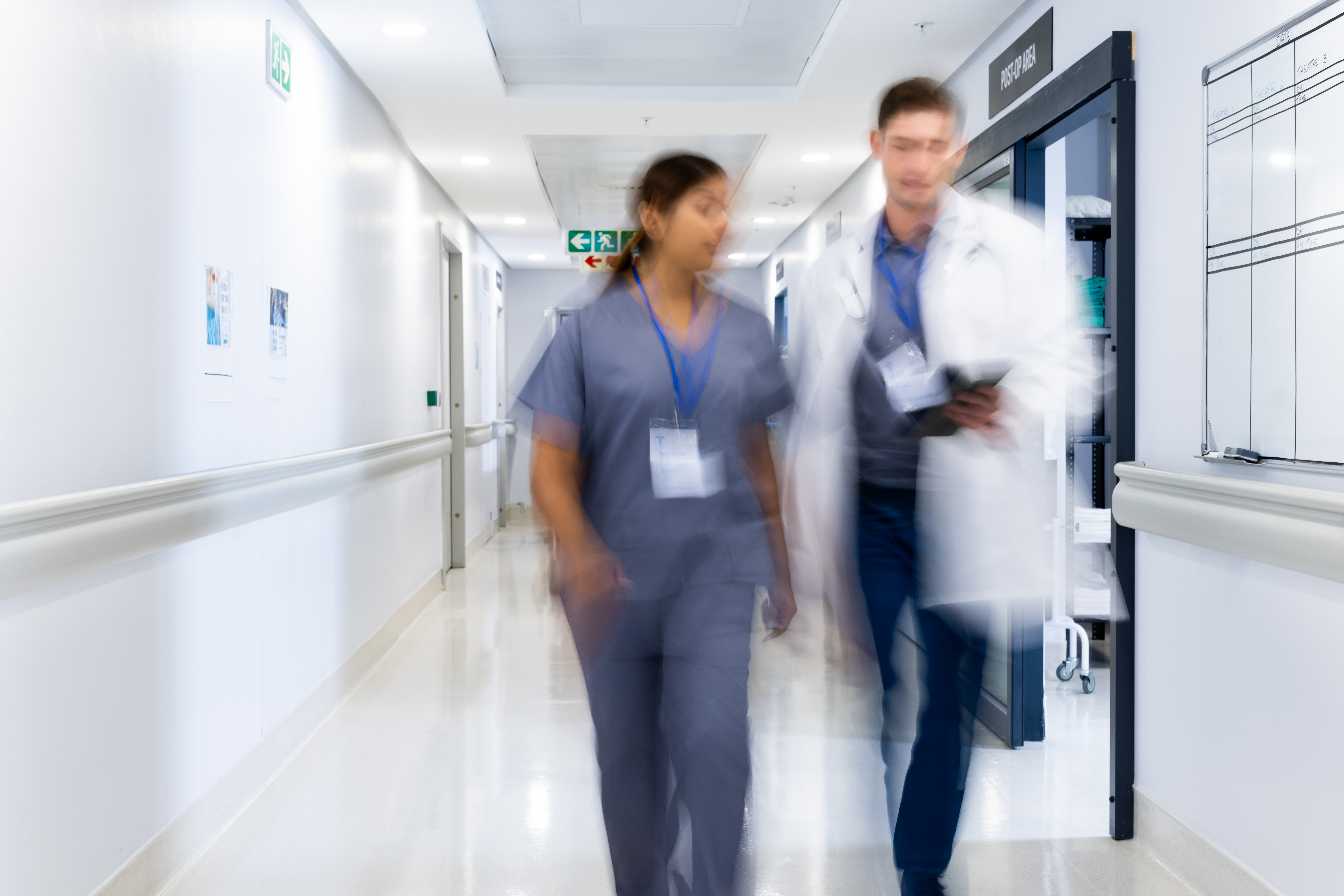 Blurred motion of diverse doctors and medical staff in busy hospital corridor, copy space. Hospital, medical and healthcare services.