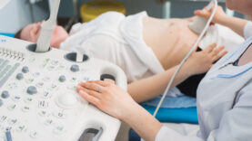 Doctor using ultrasound and screening stomach of pregnant woman