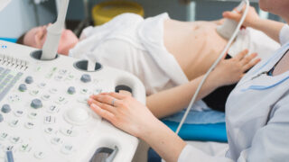 Doctor using ultrasound and screening stomach of pregnant woman