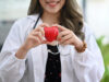 Smiling female doctor with stethoscope holding red heart. Cardio