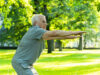 Elderly man exercising in green city park during his fitness workout