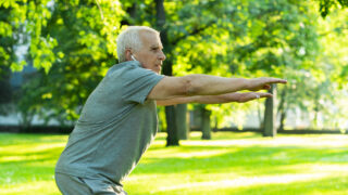 Elderly man exercising in green city park during his fitness workout