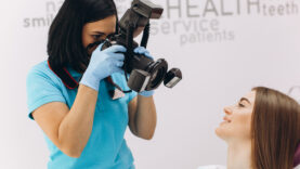 Female dentist photographs her patient’s teeth in a dental chair