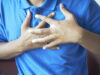 young man suffering pain in heart and holding chest with hand
