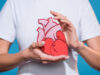 cropped shot of woman in white tshirt holding paper made heart on blue backdrop