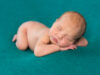 sweet newborn sleeping on stomach and hands with headband