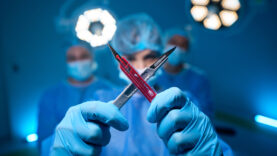 Woman doctor wearing uniform and gloves making x sign with scalpels in surgery