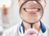 Joyful female dentist smiling through magnifier in office