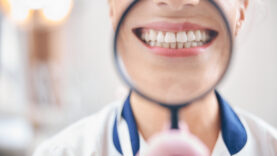 Joyful female dentist smiling through magnifier in office