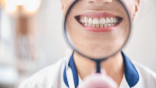 Joyful female dentist smiling through magnifier in office