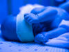 Newborn having a treatment for jaundice under ultraviolet lamp in home bed