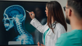 Medical team examining a head and neck x ray on a digital display