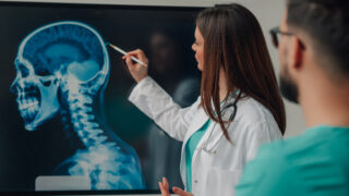 Medical team examining a head and neck x ray on a digital display