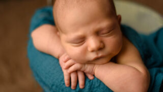Beautiful newborn baby resting her hands on her face
