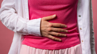 Young woman squeezing belly with hands. abdominal pain, suffering stomach ache