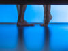 The legs of man and a woman near the bed. evening night time